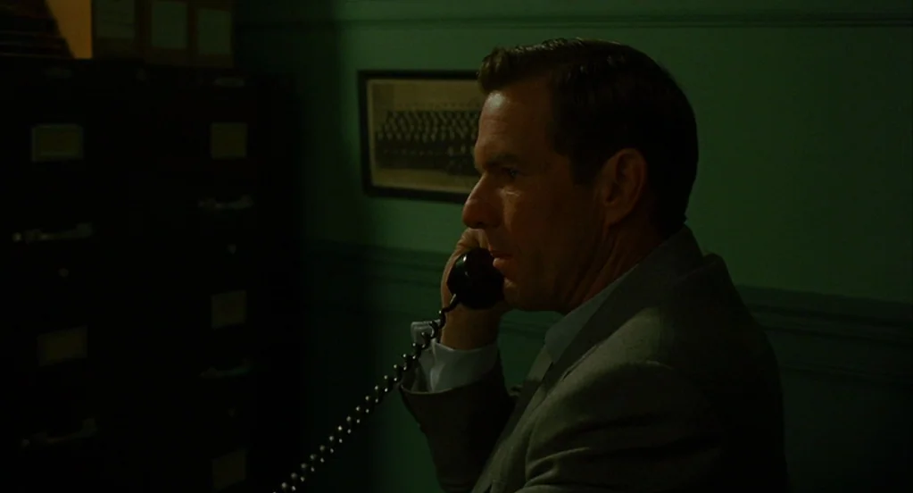Far From Heaven (2002) movie still: medium — A dimly lit room features a dark metal filing cabinet against a green wall. A man sits in profile while…