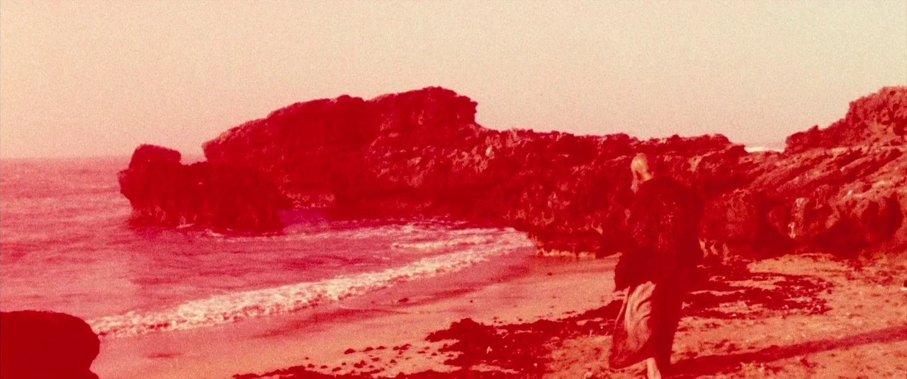 Seneca: On The Creation Of Earthquakes (2023) movie still: wide — A coastal shoreline features large dark rock formations meeting the ocean tide. A…
