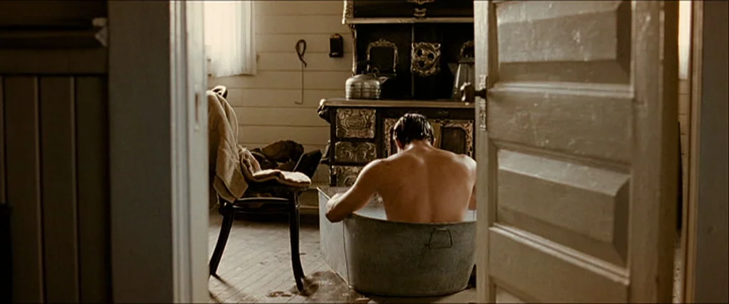 The Assassination Of Jesse James By The Coward Robert Ford (2007) movie still: medium — A rustic washroom with horizontal wood-paneled walls…