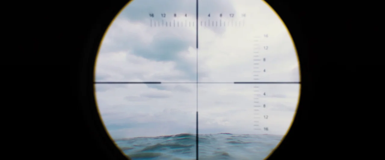 Black Sea (2014) movie still: closeup — A view through a circular sniper scope showing rippling water and a cloudy sky. The reticle is centered on…