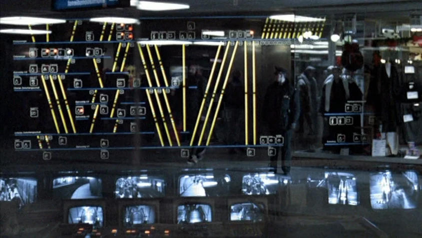 71 Fragments of a Chronology of Chance (1994) movie still: wide — A dimly lit security control center displays a glowing yellow schematic overlay on…