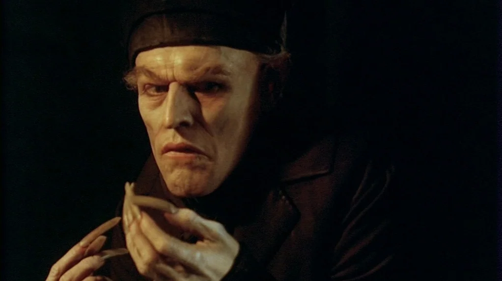 Shadow of the Vampire (2000) movie still: closeup — A man with sharp features and long claws emerges from a pitch black void. He stares directly at…