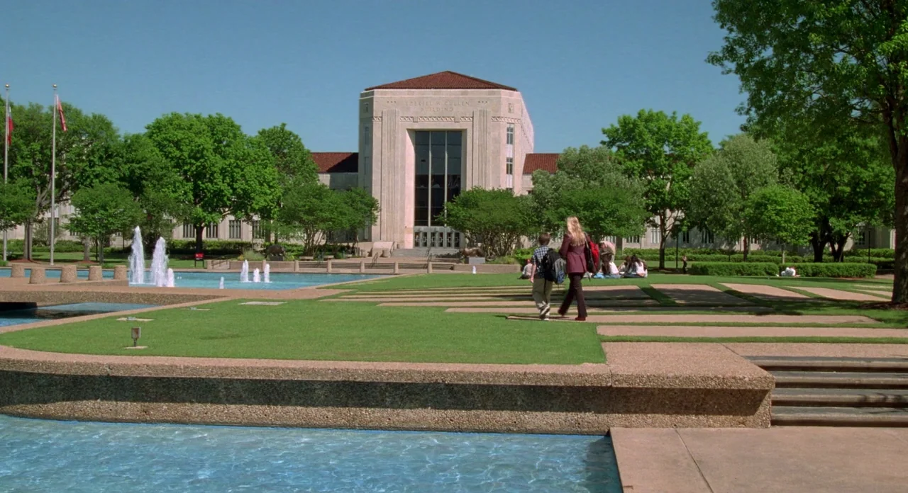 Boyhood (2014) movie still: wide — A sprawling university campus features a prominent stone building behind a large reflecting fountain. A woman and…