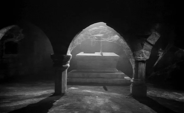 Black Sunday (1960) movie still: establishing — A dark stone crypt features arched ceilings supported by thick, ancient circular pillars. A raised…