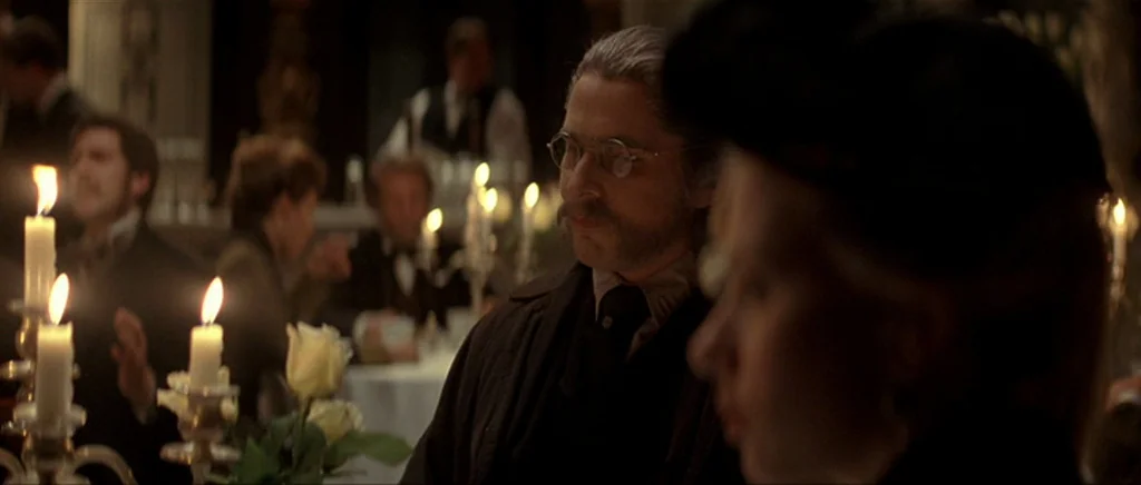 The Prestige (2006) movie still: medium — A dimly lit banquet or dining hall features guests seated at white-clothed tables. A man with a mustache…