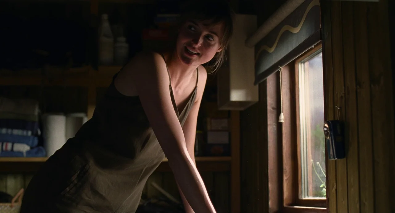 The Worst Person in the World (2021) movie still: medium — A dark wooden shed with shelves containing household items stands in the shadows. A young…