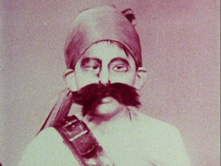 Emperor Tomato Ketchup movie still: closeup — A portrait of a man with a thick mustache and darkened eyes. The subject is framed tightly from the…