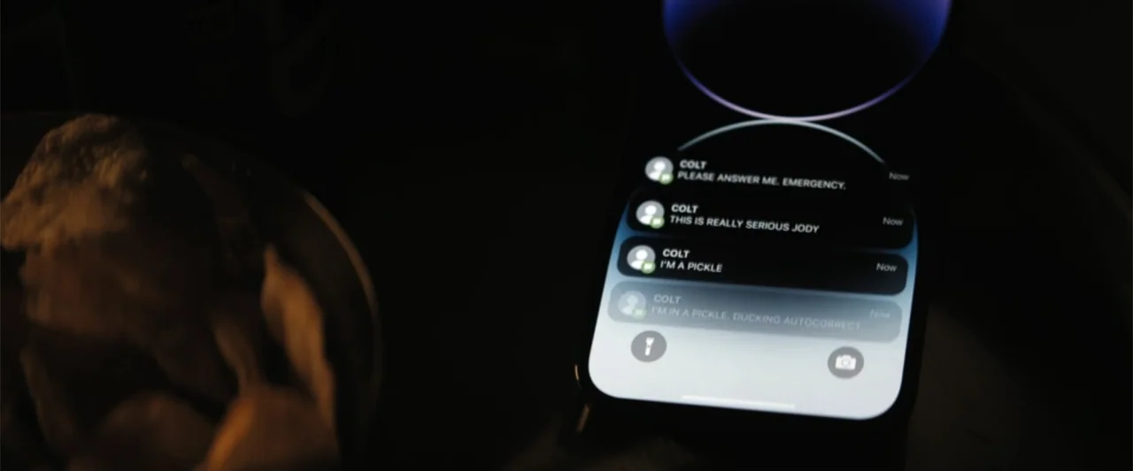 The Fall Guy (2024) movie still: closeup — A dark, dimly lit environment features a modern smartphone screen in the foreground. The screen displays…