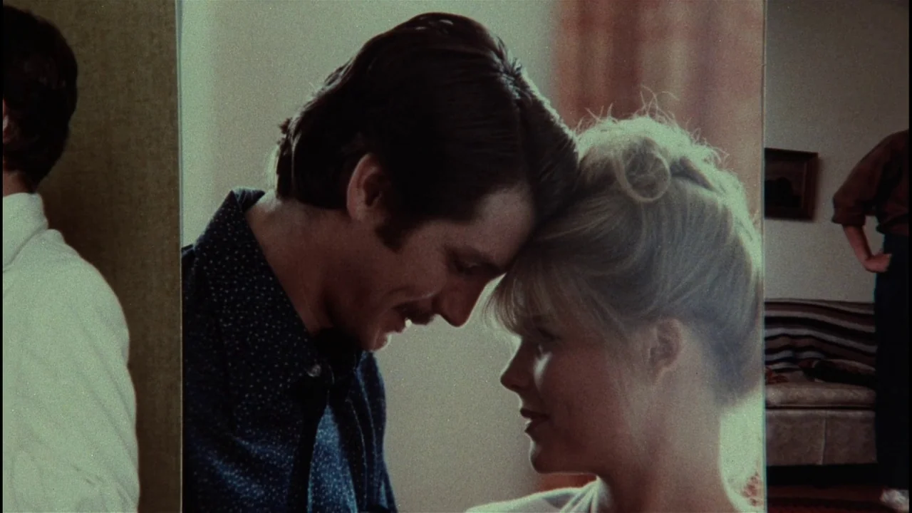 Star 80 (1983) movie still: medium — A light-filled living room shows a man and woman leaning their foreheads together. The frame is presented as if…