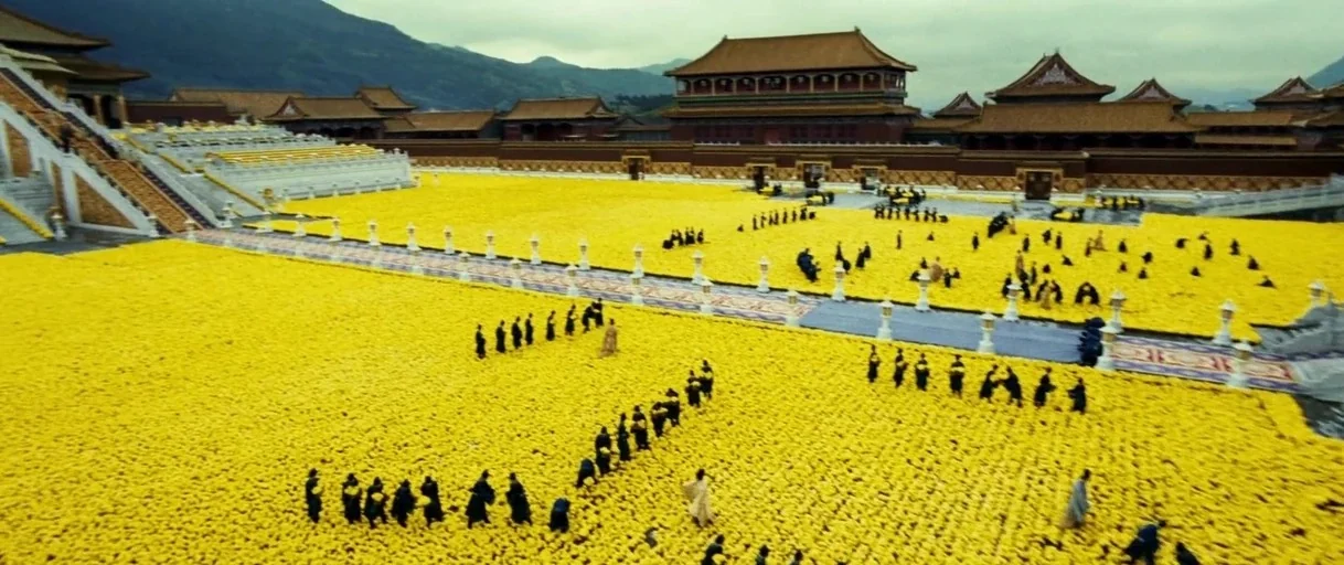 Curse of the Golden Flower (2006) movie still: wide — An immense outdoor palace courtyard is entirely covered in a thick layer of yellow flowers.…
