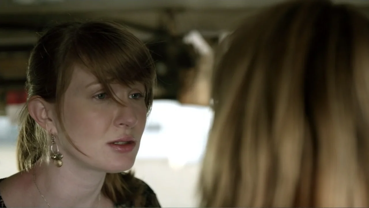 Free Samples (2013) movie still: closeup — A well-lit indoor space with blurred background details. A woman in her thirties looks toward someone out…