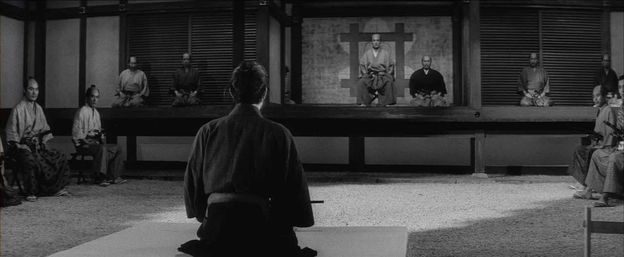 Harakiri (1962) movie still: wide — A traditional Japanese dojo interior with a gravel floor and wooden partitions. A single man in the foreground…