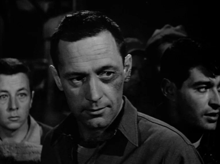 Stalag 17 (1953) movie still: medium — A dimly lit, cramped interior space filled with several men standing close together. The men appear to be in…