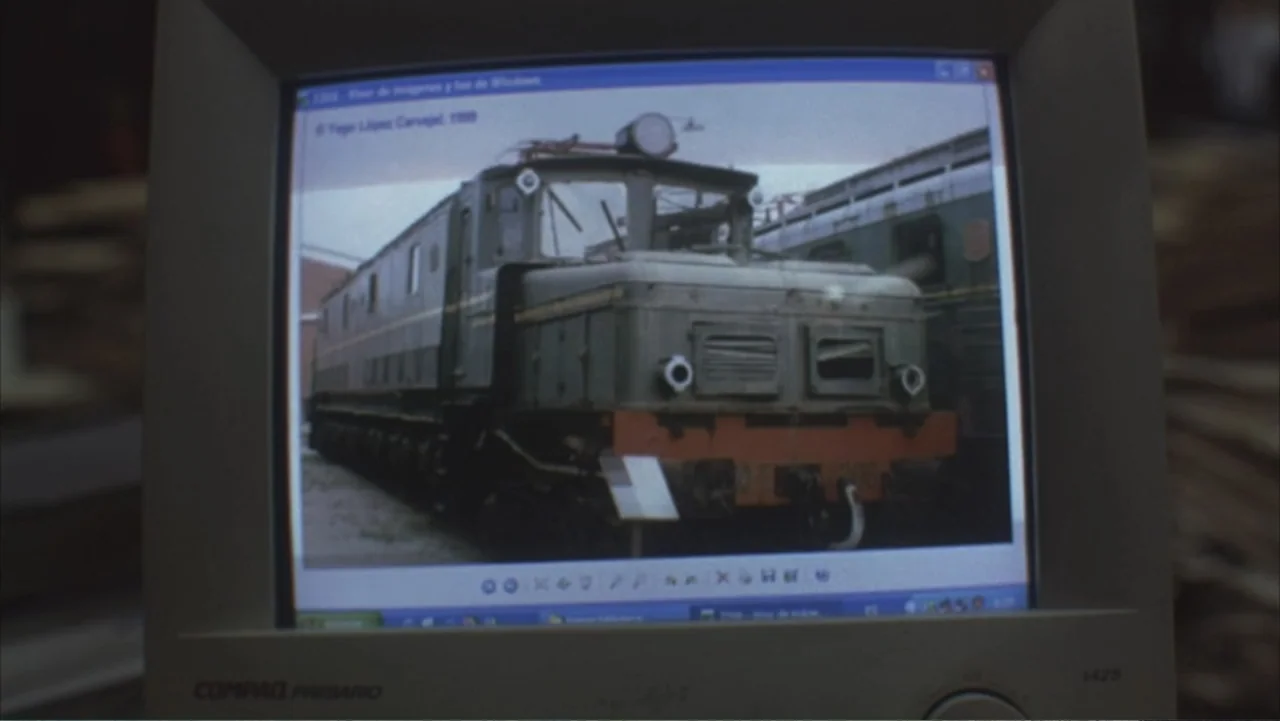 A Distant Place (2020) movie still: closeup — A close-up of a bulky CRT computer monitor showing a vintage diesel locomotive image. The digital…