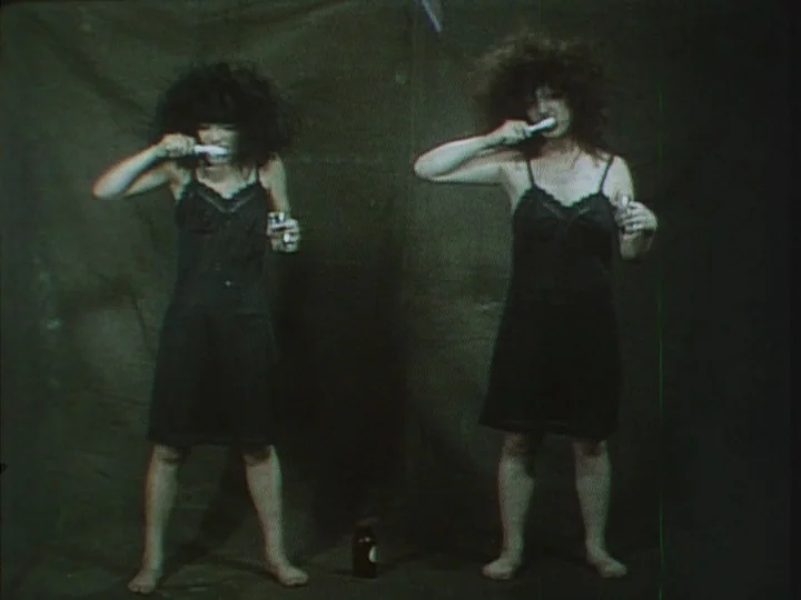 A Tale of Smallpox (1975) movie still: fullbody — Two women stand before a dark, creased fabric backdrop in a minimalist interior space. They…