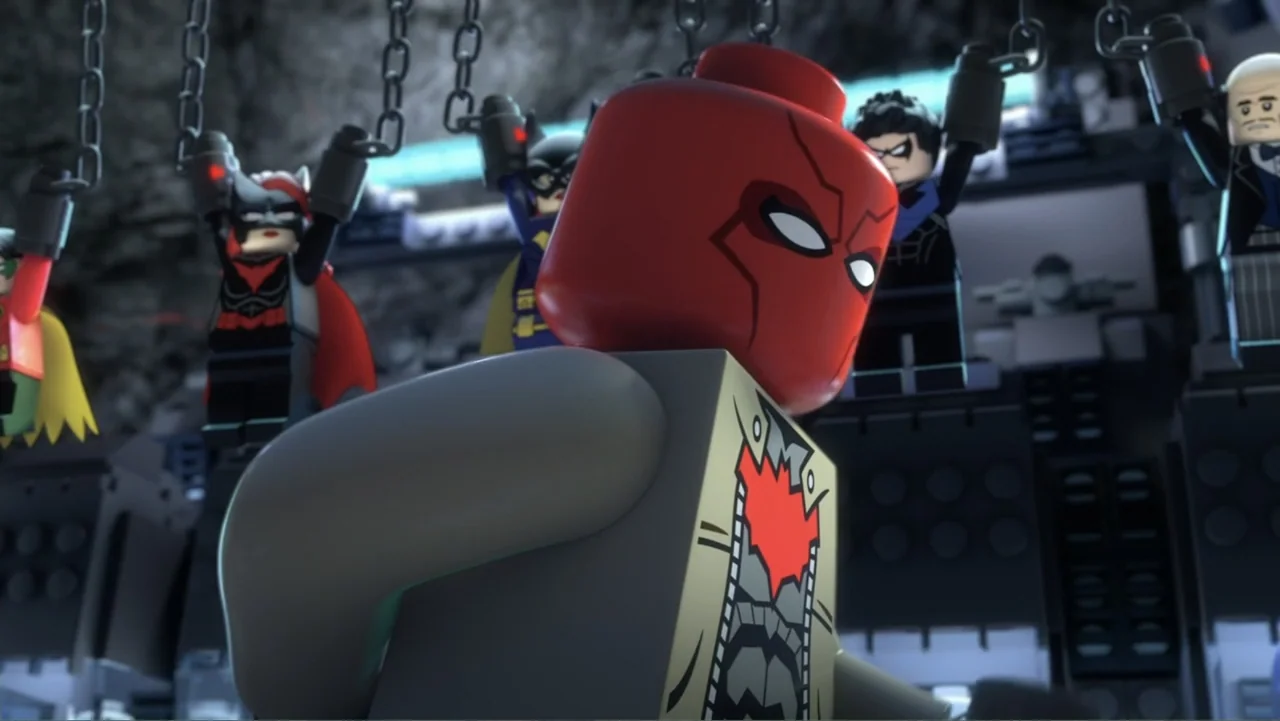 LEGO DC Batman: Family Matters (2019) movie still: medium — A rocky cavern interior contains several plastic toy figures suspended by silver chains.…