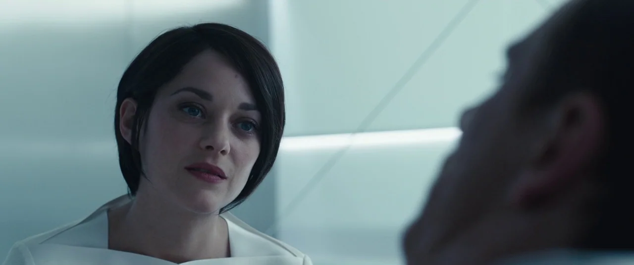 Assassin’s Creed (2016) movie still: closeup — A sterile room with smooth white surfaces and soft, diffused illumination. A woman with dark hair…