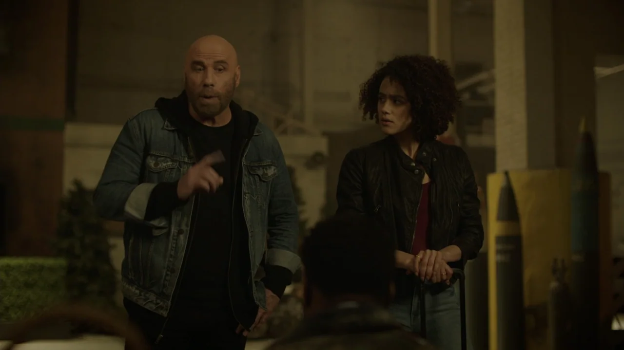 Die Hart (2023) movie still: medium — An interior industrial structure with muted lighting and visible equipment in the background. A man talks to a…