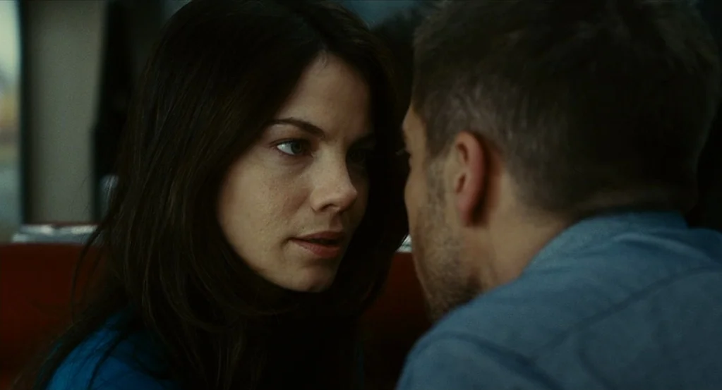 Source Code (2011) movie still: closeup — A close-up view shows a man and woman in a booth. The woman maintains direct eye contact with the man…