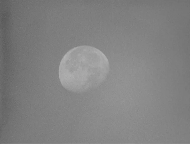 The Ascent (1977) movie still: establishing — The moon appears as a bright, circular celestial body in a vast dark sky. The surface features of the…