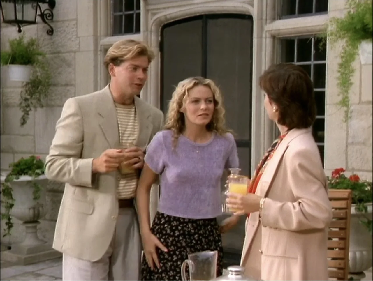 At the Midnight Hour (1995) movie still: medium — A stone patio area features large potted plants and a classic architectural doorway. Three…