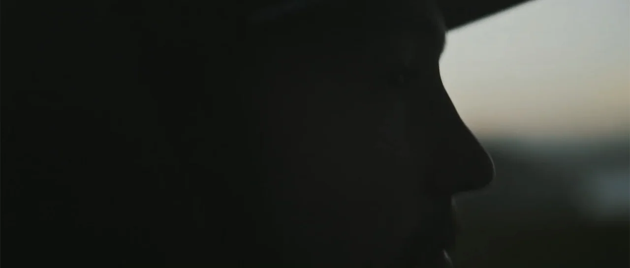 Taking Back the Waves (2017) movie still: closeup — A profile view of a person inside a vehicle silhouetted against a bright background. The subject…