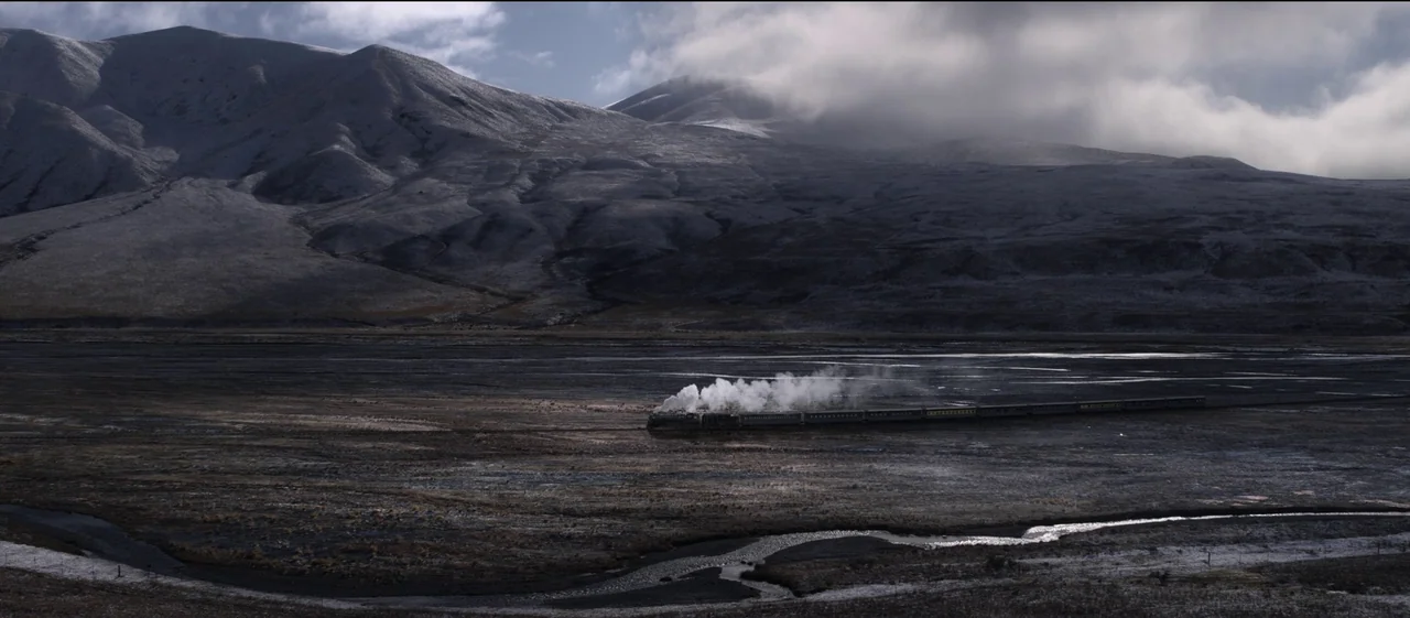 The Power of the Dog (2021) movie still: establishing — A vast, snow-dusted valley is overlooked by large, rolling, partially obscured mountains. A…