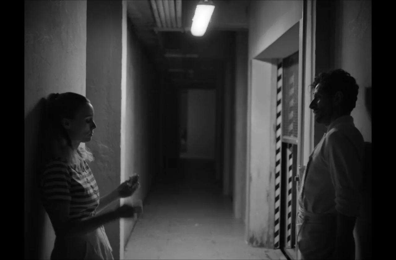 The Kitchen (2012) movie still: medium — A narrow industrial corridor features concrete walls and a single ceiling-mounted fluorescent light…
