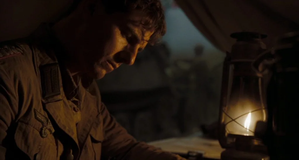 Valkyrie (2008) movie still: medium — A dimly lit military tent at night features a man in uniform working intently. He leans over a desk while an…
