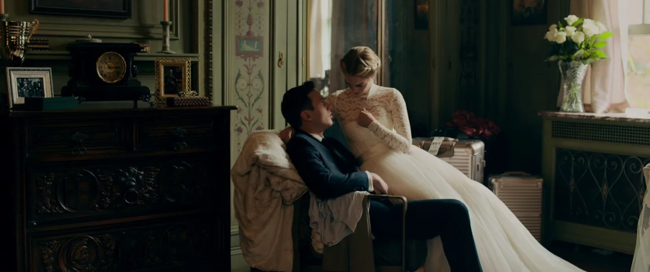 Ready or Not (2019) movie still: medium — An upscale hotel room features ornate green walls, dark wood furniture, and vintage decor. A man in a suit…
