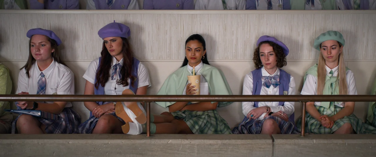 Do Revenge (2022) movie still: medium — A group of young women sit in a row on school bleachers against a wall. They wear matching pastel uniforms…