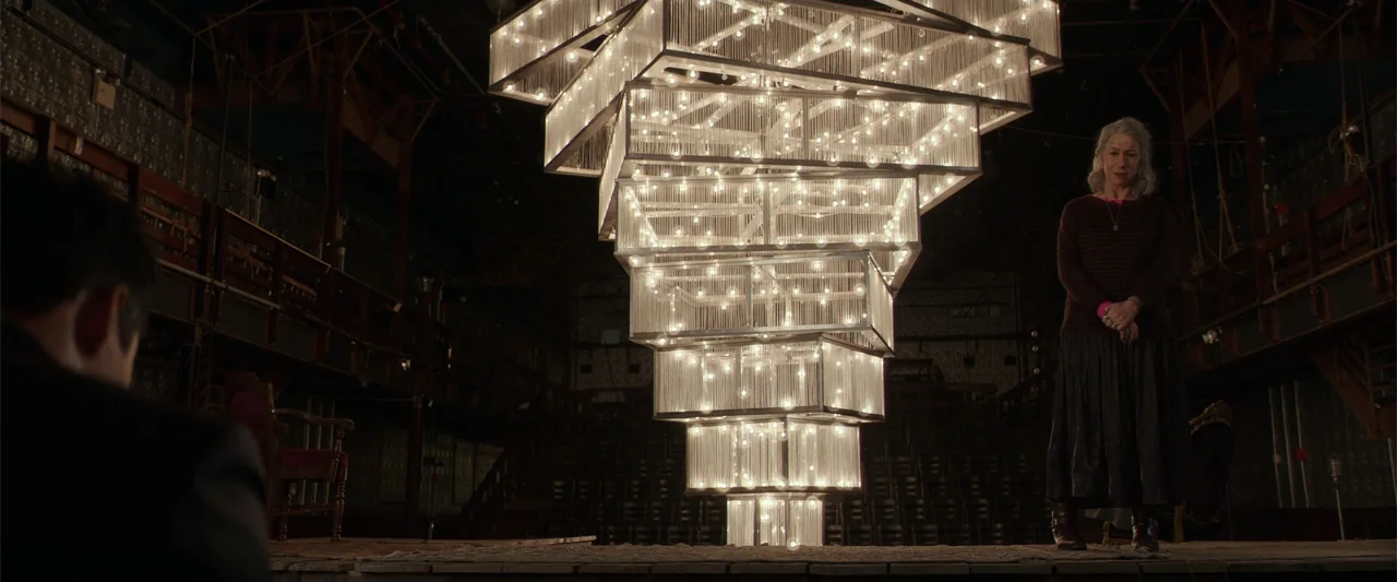 Collateral Beauty (2016) movie still: wide — A dimly lit empty theatrical stage features a massive illuminated geometric sculpture made of glass. A…