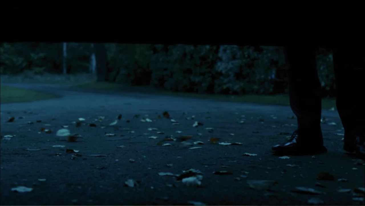 Before I Go to Sleep (2014) movie still: wide — A dark paved driveway is covered in scattered dry autumn leaves at night. A person's legs and feet…