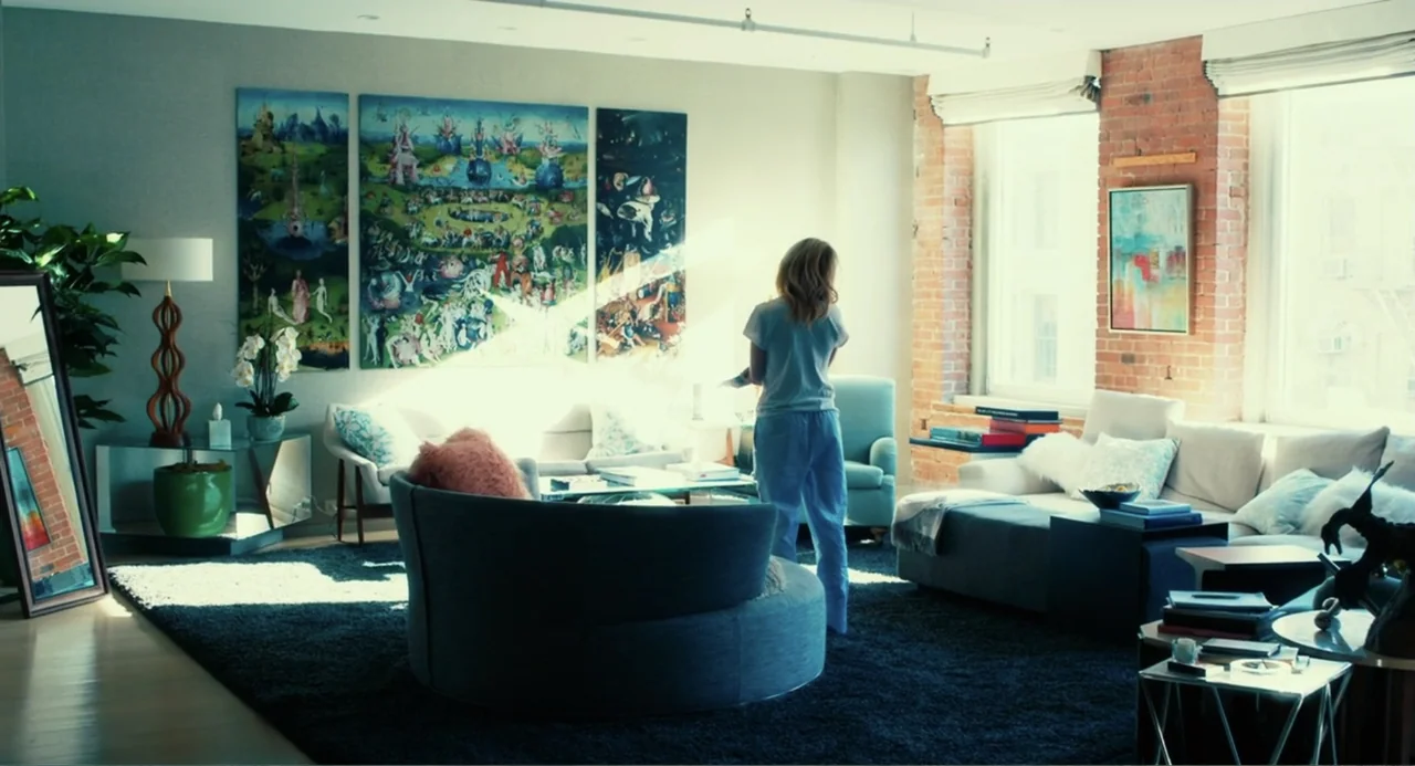 An Imperfect Murder (2017) movie still: wide — A well-lit contemporary apartment features a large triptych painting and exposed brick accents. A…