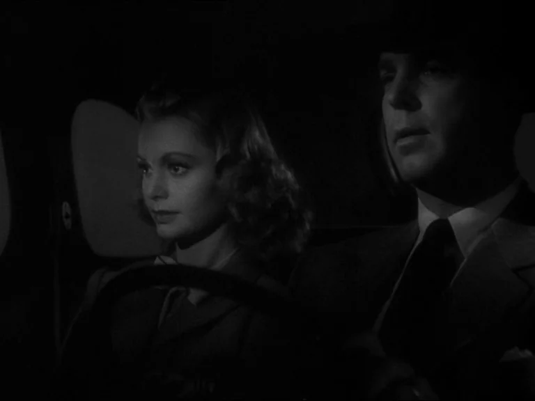 Double Indemnity (1944) movie still: medium — A dark car interior at night with a man driving and a woman passenger. Both individuals face forward…