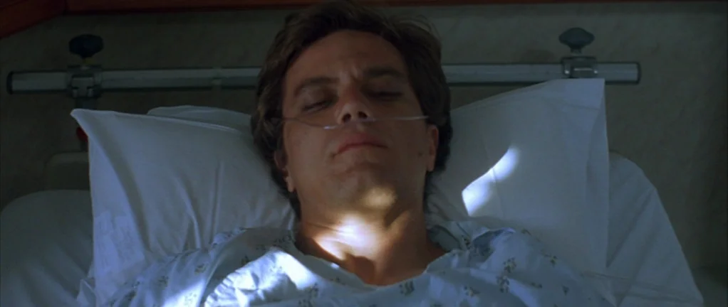Shotgun Stories (2007) movie still: closeup — A man lies on a hospital bed with thin nasal cannula tubing. He rests on white pillows while sunlight…