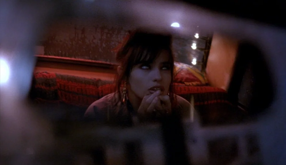 Night on Earth (1991) movie still: closeup — The interior of a parked van at night features a red textured blanket. A young woman stares upward with…