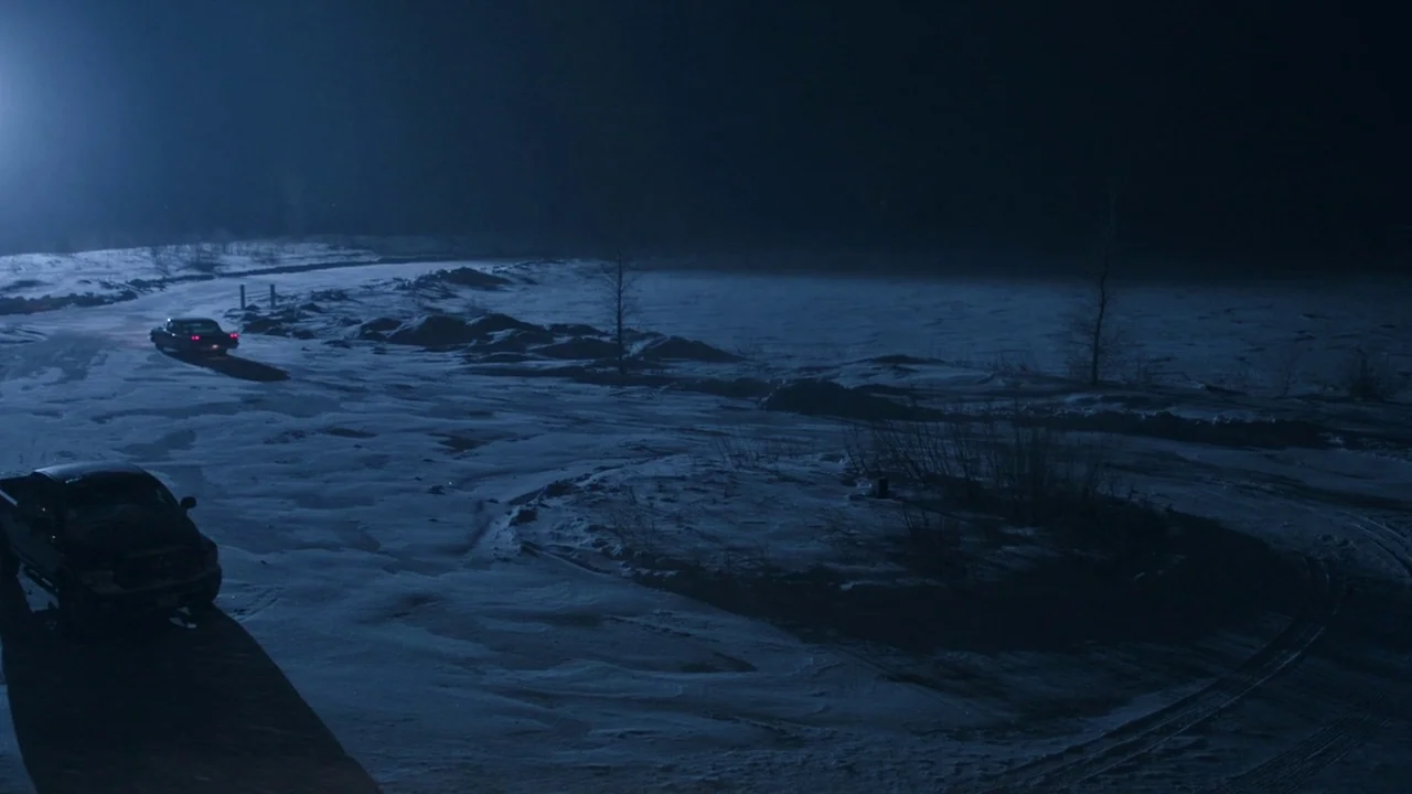 Cult of Chucky (2017) movie still: wide — A vast, snow-covered landscape stretches under a dark night sky with sparse vegetation. Two dark vehicles…