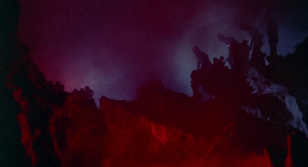 Planet of the Vampires (1965) movie still: wide — A jagged volcanic terrain is illuminated by intense red light from below. Thick smoke drifts…