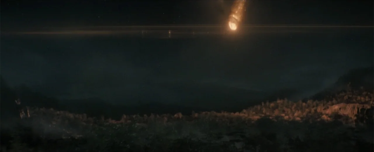Venom: The Last Dance (2024) movie still: establishing — A dark, mountainous landscape stretches under a black night sky at horizon level. A glowing…