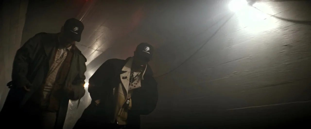 The Last Boy Scout (1991) movie still: medium — A dark concrete tunnel with a single overhead light casting long shadows across walls. Two men walk…