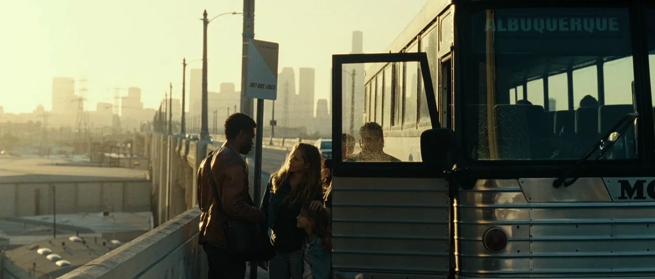 Message From The King (2016) movie still: wide — An overpass highway during sunset overlooks a distant urban skyline in the haze. A man and a woman…
