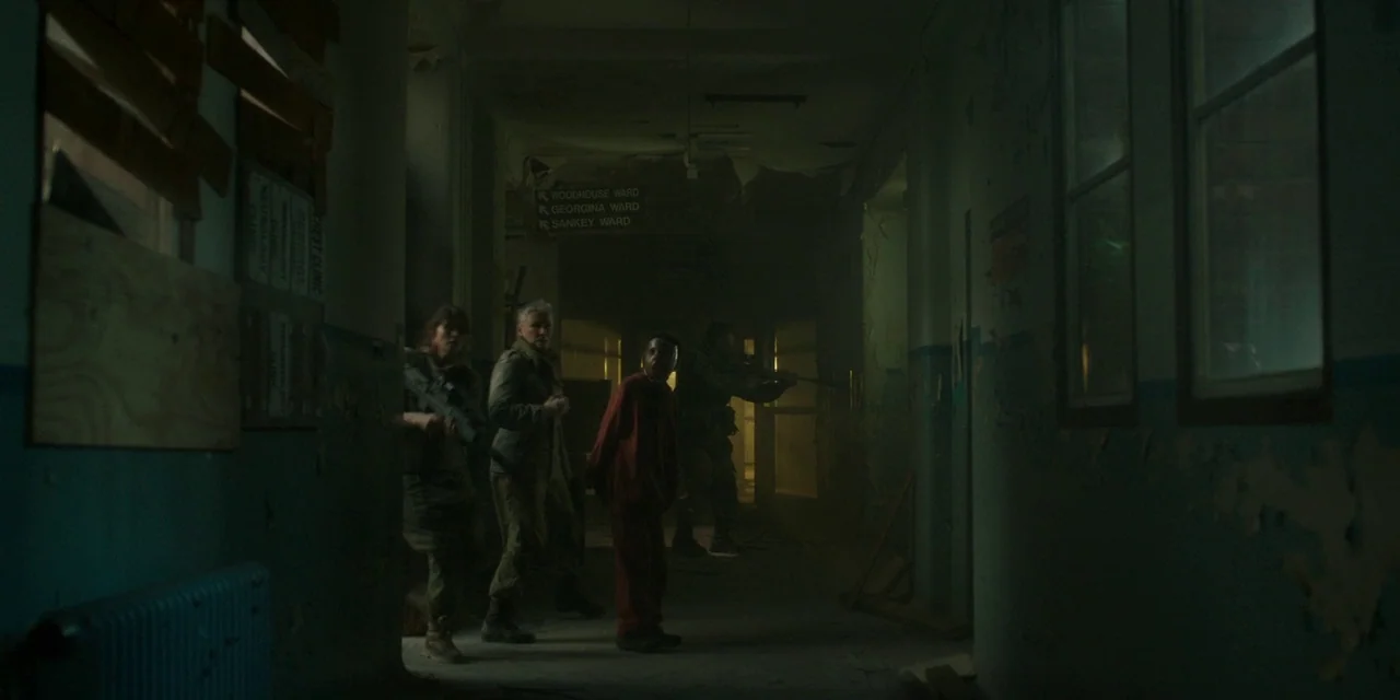 The Girl With All The Gifts (2016) movie still: wide — A dark, neglected hospital corridor features peeling paint, boarded-up windows, and…