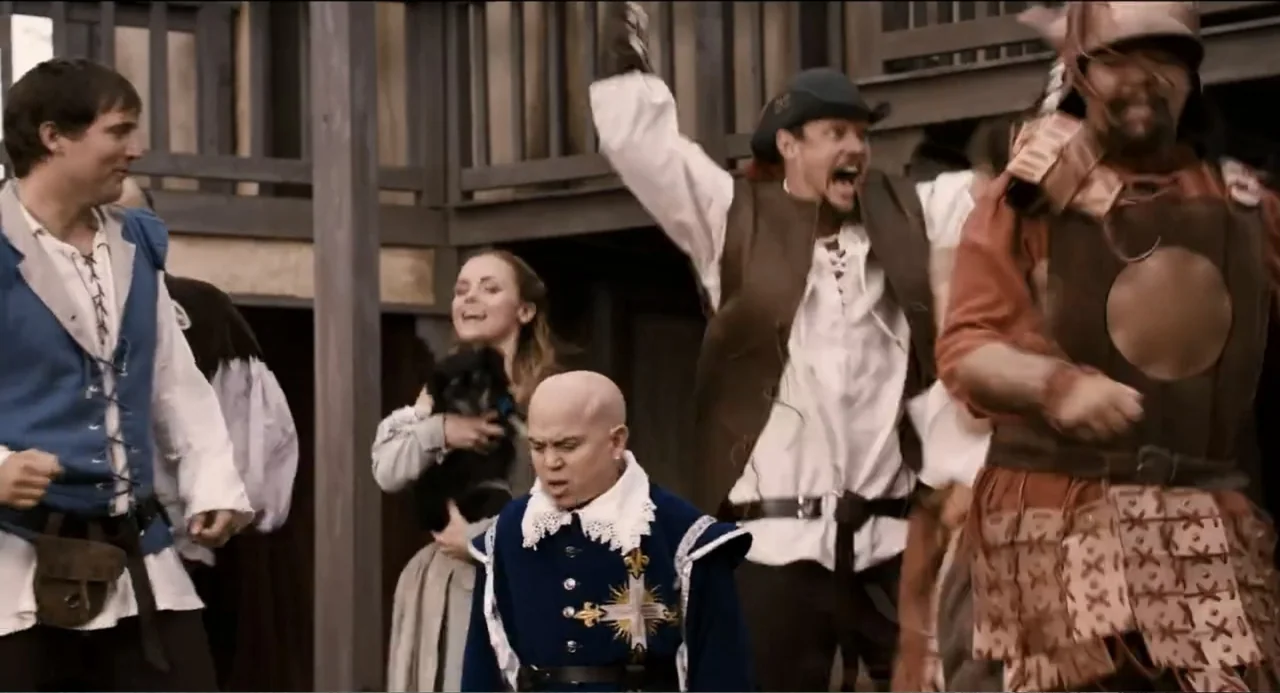 Todo es amor (2024) movie still: fullbody — A group of people wearing medieval-style period costumes stand outdoors before a timber structure.…