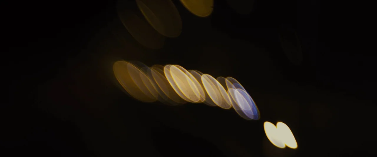 Locke (2013) movie still: establishing — An out-of-focus night view captures multiple circular light reflections against a black void. These…
