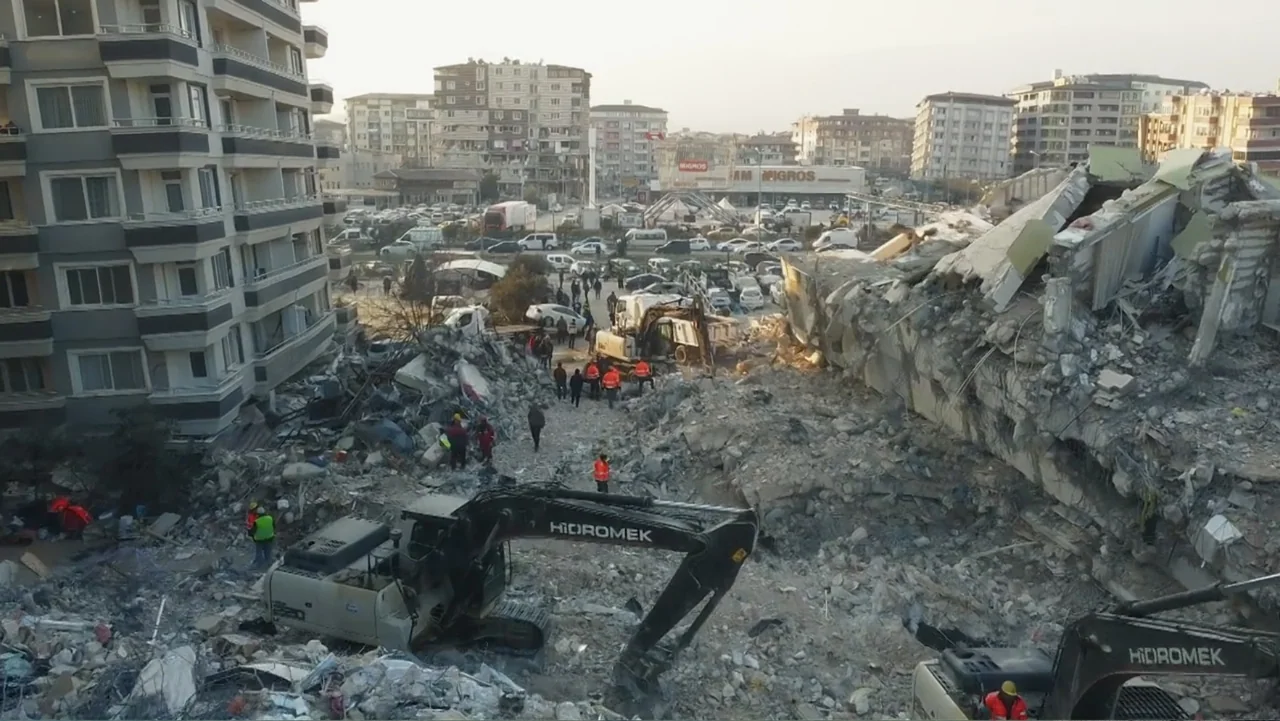 Death Without Mercy (2024) movie still: wide — A dense urban disaster site features collapsed concrete buildings and heaps of pulverized debris.…