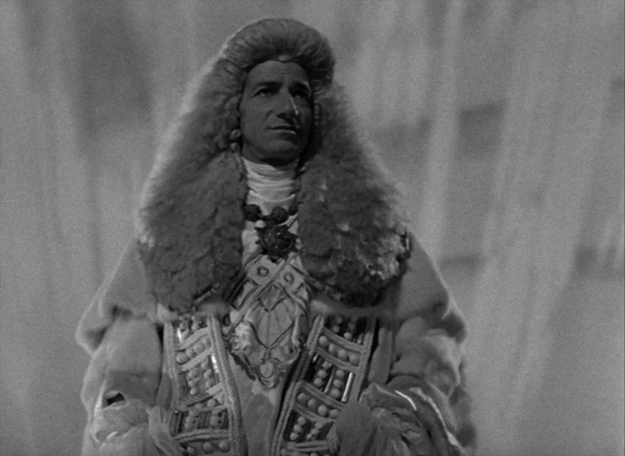 A Matter of Life and Death (1946) movie still: medium — An interior space features a stylized, draped background behind a centrally positioned man.…