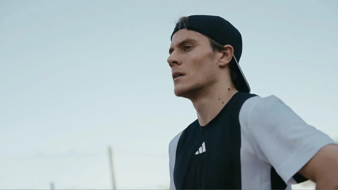 FRAGILE - The story of Nicolò Fagioli (2024) movie still: medium — An outdoor athletic area with a bright overcast sky in the background. A young…