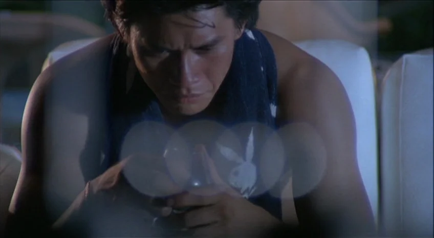 Boxer’s Omen (Mo) (1983) movie still: medium — A dimly lit room provides the backdrop for a young man sitting quietly. He focuses his attention on…