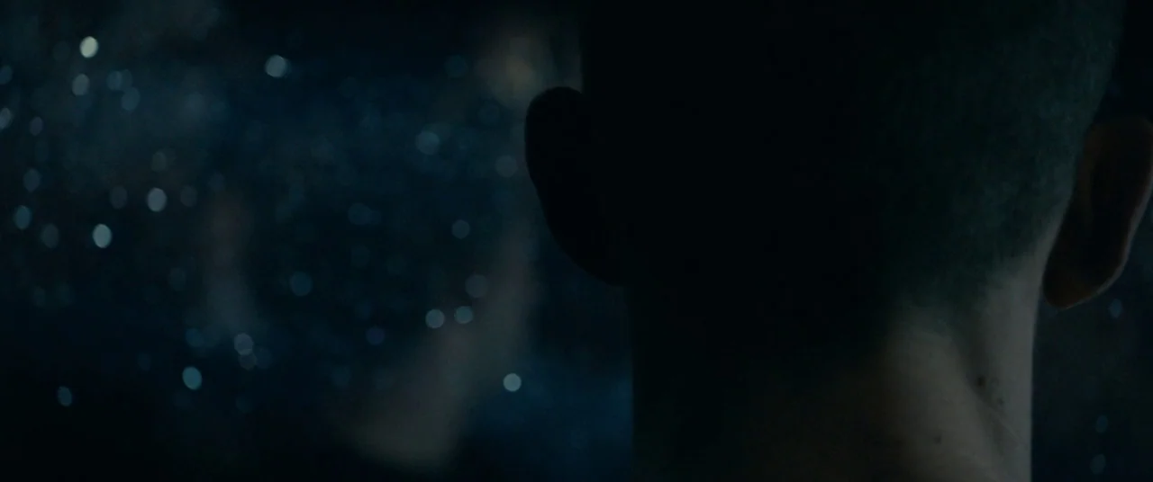BPM (Beats Per Minute) (2017) movie still: closeup — A close up of a person's head from behind in a dark, indistinct space. Circular bokeh patterns…